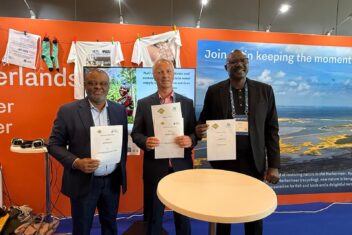 Three representatives from WASTE, AfWASA and PASA holding up signed MoU