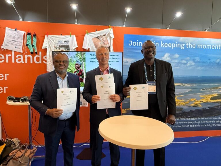 Three representatives from WASTE, AfWASA and PASA holding up signed MoU