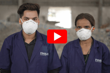 A man and woman stood next to each other with white PPE masks on, ear plugs and blue FINILOOP uniforms